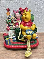 Front view of resin Winnie the Pooh stocking holder with chair, tree, gifts, hook visible