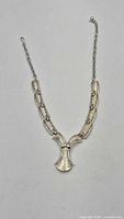 Full front view of articulated silver-tone necklace with central pendant