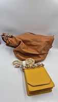 Front view Ralph Lauren tan leather bag with yellow pouch in foreground