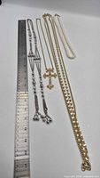 Group of five necklaces laid beside ruler for scale