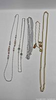 Group shot of all five necklaces laid out to show styles and lengths