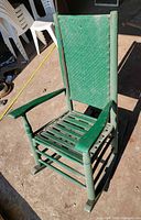 Front view of green wooden rocking chair with wicker back and slatted seat