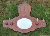 Front view showing wood rack with four antler hooks and central oval mirror opening