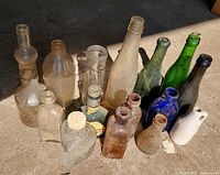 Front view of all sixteen bottles standing on concrete floor