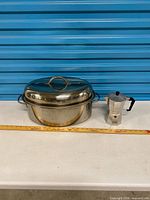 Full view of roasting pan with lid and moka pot beside ruler for scale