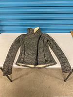 Full view of grey knit Bench jacket laid flat showing exterior, zipper, pockets, collar