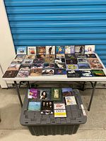 Overall shot of roughly 40 CDs on table above storage bin