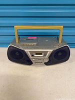 Front view of Panasonic RX-D11 boombox showing speakers, display, cassette deck, handle