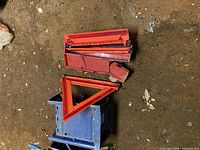 Stacked red folding warning triangles on floor