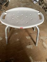 Top view of white plastic bath seat with handles and adjustable legs
