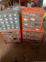 Three orange drawer organizer cabinets filled with assorted fasteners