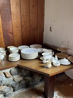 Stacks of plates, bowls, cups and serving pieces on corner table