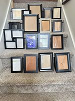 Seventeen black frames of various sizes arranged on staircase