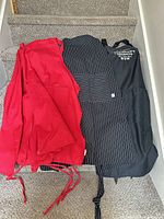 Four aprons laid out on stairs: two red, one pinstripe, one black with rum branding