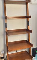 Front view of five-shelf wooden leaning bookcase showing shelves and side guards