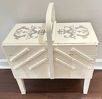 Cabinet closed, front and top view showing cream paint, stencil, legs and handle