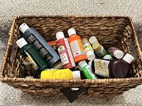 Top view of basket showing numerous acrylic paint bottles and basket construction