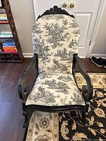 Front view of black wooden rocking chair with toile upholstery