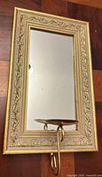 Front view showing entire gold framed mirror and brass candle holder
