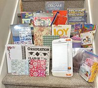 Group shot showing all craft books, albums, paper pads, paper trimmer, yarn and LEGO roses kit on stairs