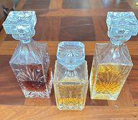 Front view of three square cut-crystal decanters with stoppers