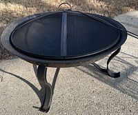Side view of assembled fire pit on three legs with mesh screen and poker