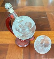Globe decanter on wooden stand alongside matching etched glass