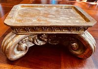 Front view of gold pedestal candle holder showing ornate scrolled base