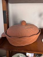 Terra cotta covered cooker on shelf