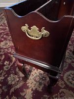 Side view showing brass handle, cabriole leg and finish