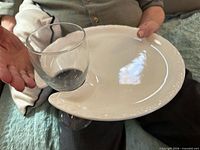 Person holding white ceramic buffet plate showing wine glass notch