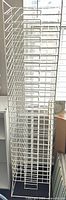 Full view of tall white wire rack with multiple angled shelves