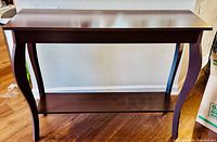 Front view of dark stained wood sofa table showing top, curved legs, and lower shelf