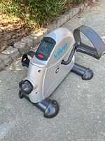 Left front view showing LCD display, tension knob, pedals, stabilizer feet