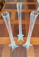 Three tall clear glass vases standing on wood table