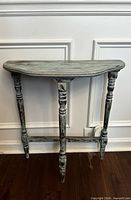 Front view of teal distressed demilune table showing turned legs and stretcher