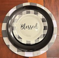 Stacked view showing plaid charger, black dinner plate, and Blessed salad plate