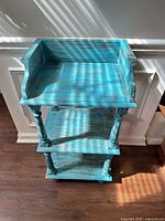 Front view of turquoise three-shelf stand