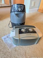 Honeywell air purifier, Sunbeam humidifier and Honeywell manual grouped on carpet