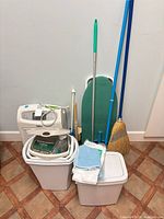 Group shot showing dehumidifier, two bins, ironing board, broom and other tools