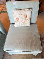 Front view of seafoam blue armless chair with floral pillow