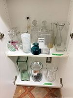 Entire lot inside cabinet showing decanters and vases on two shelves