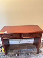 Front view of mahogany console table with two wicker drawers