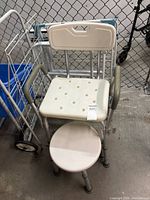Shower chair, round stool, folding rail/frame visible