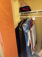 Closet view showing hanging coats, shawl and stack of hats