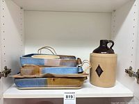 All four stacked stoneware baking dishes and jug on shelf