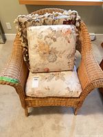 Front view of wicker chair with cushions and decorative pillow