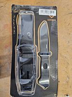 Front view of retail package showing knife, sheath and strap