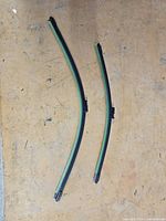 Two new windshield wiper blades of different lengths on a work surface