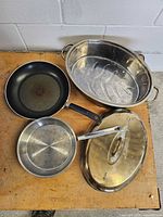 All cookware items laid out including roaster, lid, frying pan, saucepan